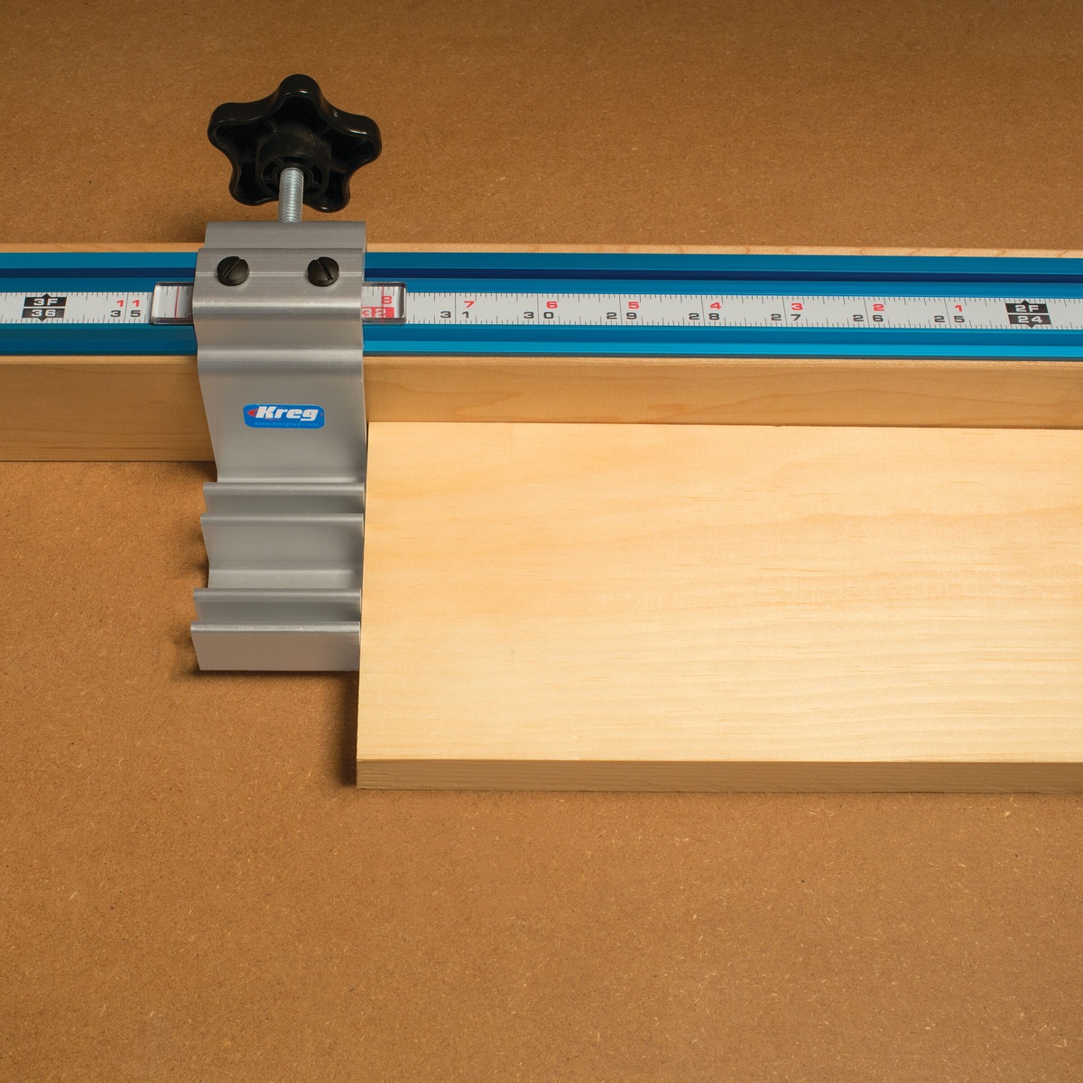 Kreg KMS7800 Production Stop set against a board on a shop fence for repeatable woodworking cuts at a miter saw station