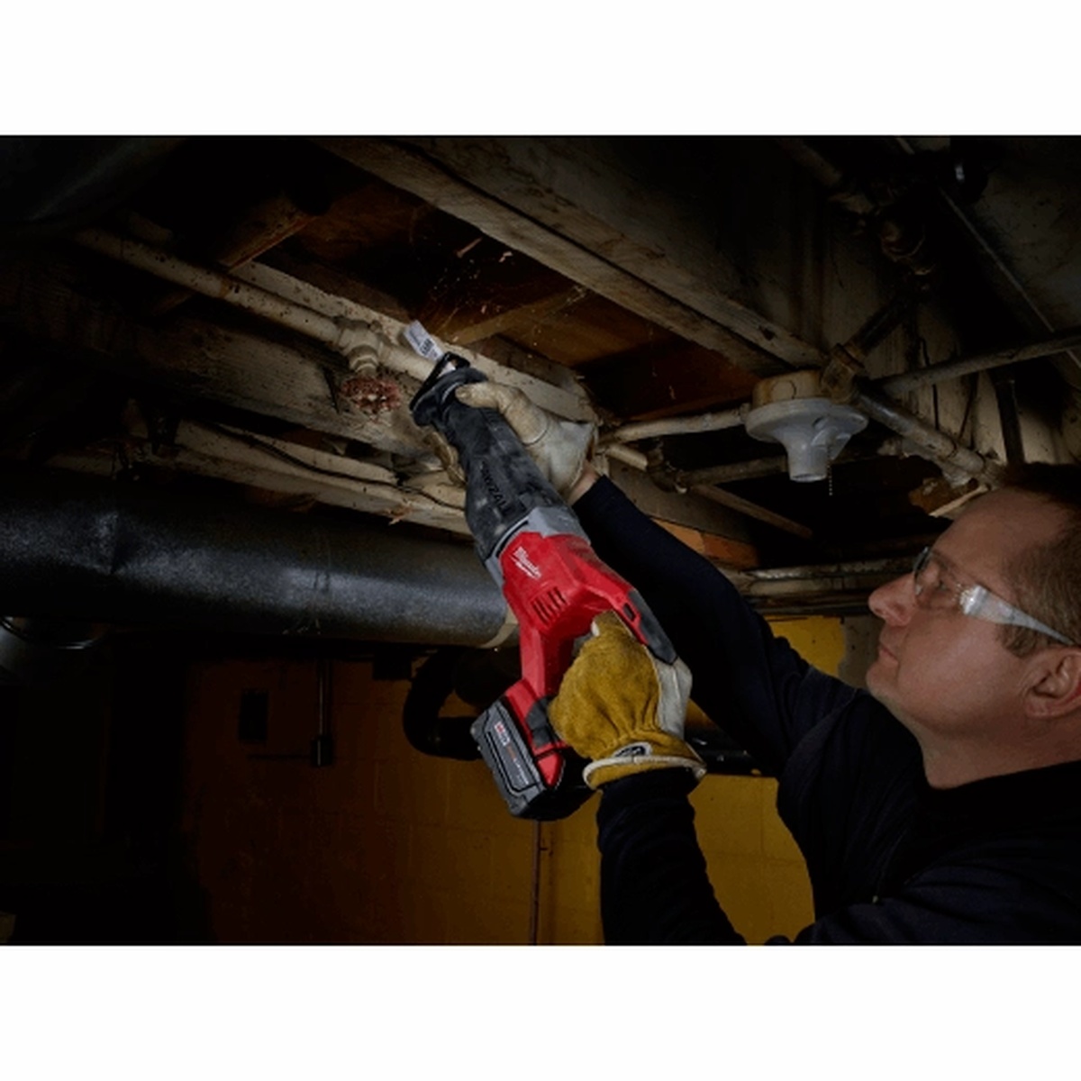 Milwaukee M18 SAWZALL Reciprocating Saw making an overhead cut on pipe in a basement mechanical space