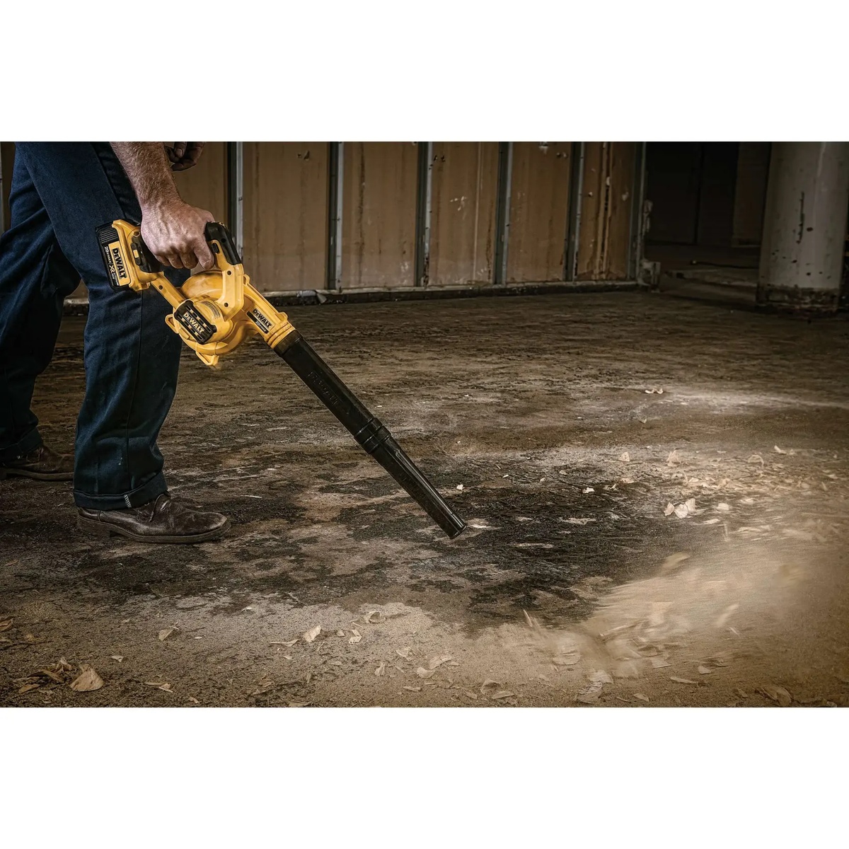 DEWALT DCE100M1 20V MAX Cordless Jobsite Compact Blower Kit clearing dust and debris across a concrete floor during indoor jobsite cleanup