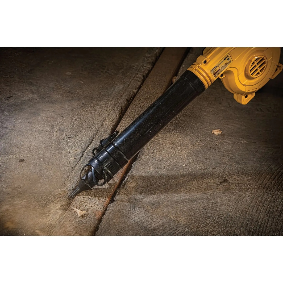 DEWALT DCE100M1 20V MAX Cordless Jobsite Compact Blower Kit directing airflow into a narrow floor seam for precise debris removal on concrete