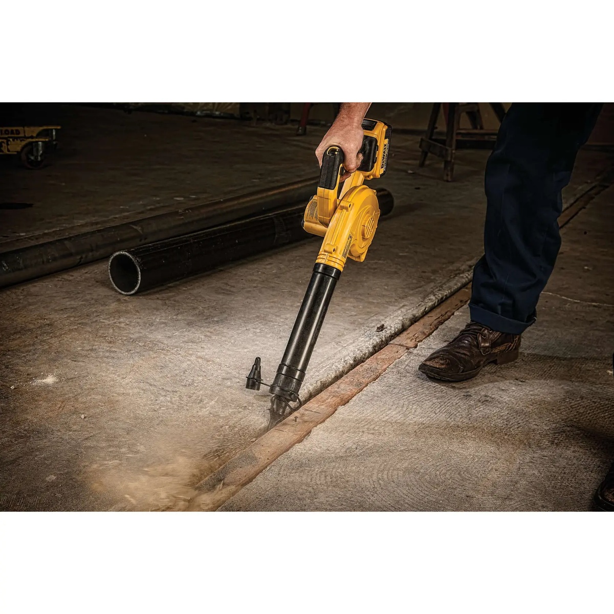DEWALT DCE100M1 20V MAX Cordless Jobsite Compact Blower Kit being used one-handed to clean a concrete floor seam in an indoor work area
