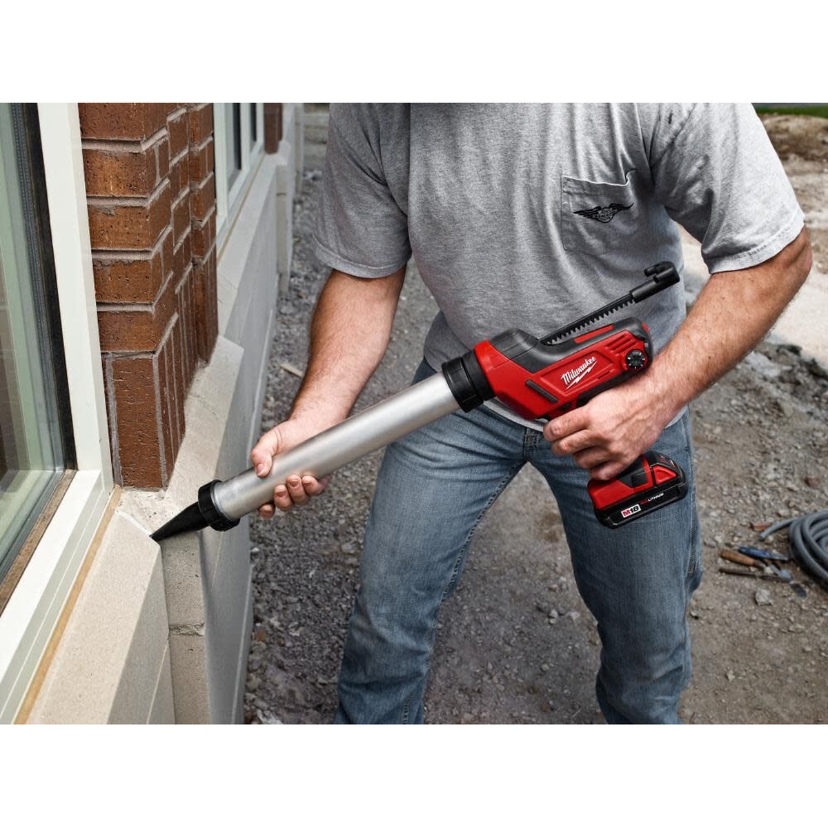 Milwaukee 48-08-1093 20oz Aluminum Sausage Conversion Kit dispensing sealant along exterior masonry at a window opening on a jobsite