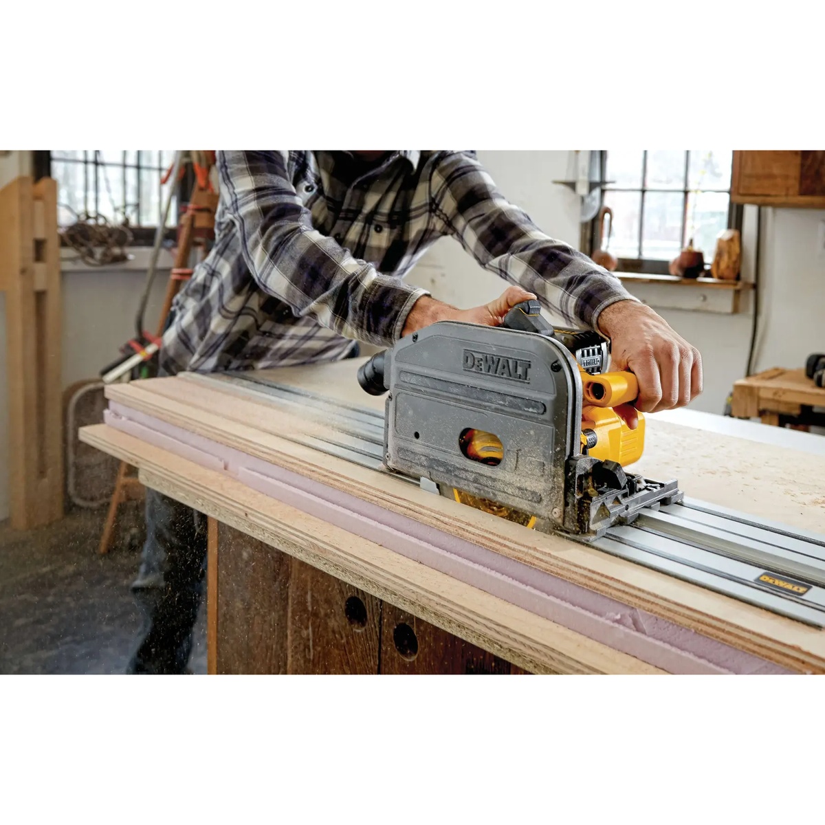 DeWALT DCS520ST1 60V MAX Brushless Cordless 6-1/2 in. Track Saw Kit cutting a long straight line through plywood on a workshop bench with guide rail support