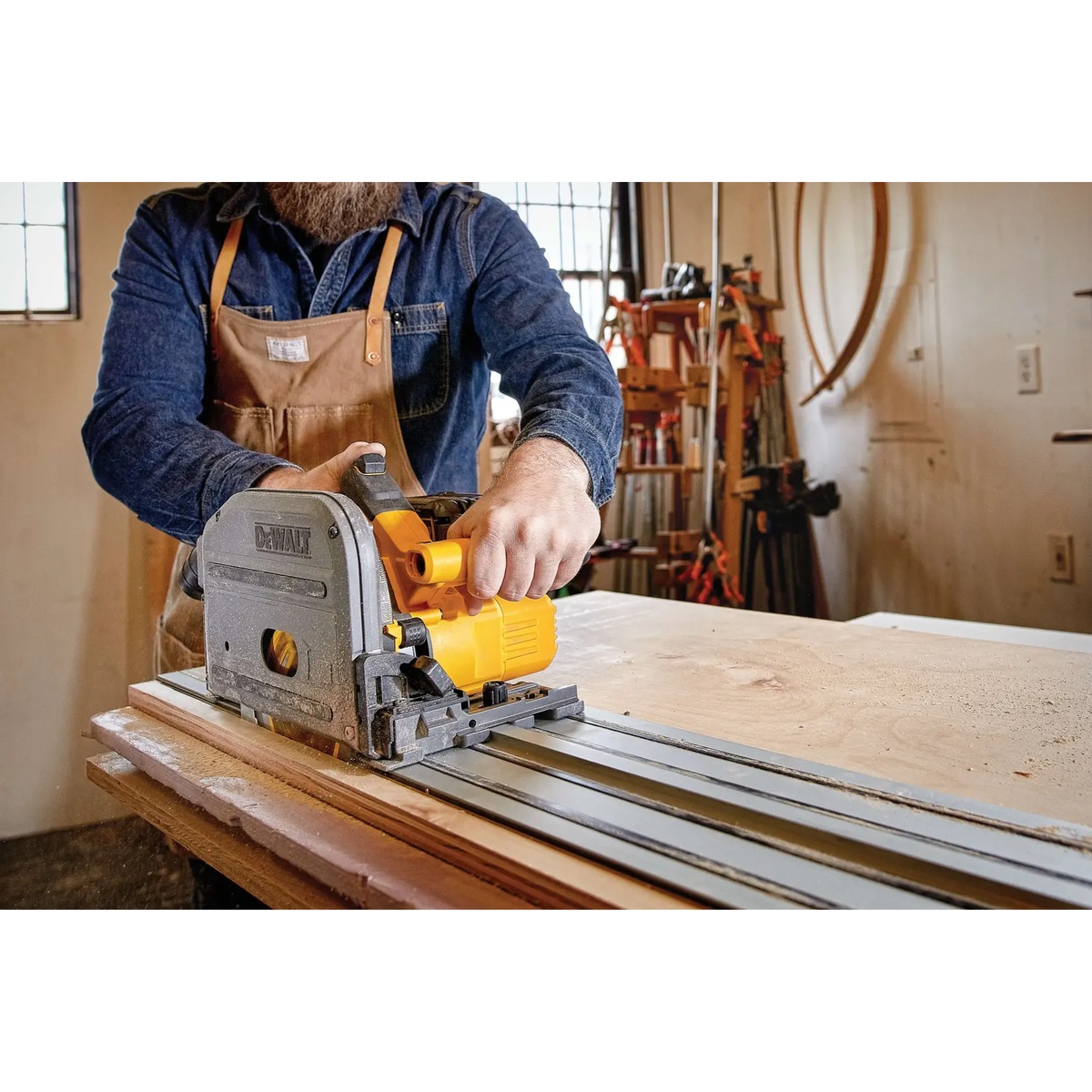 DeWALT DCS520ST1 60V MAX Brushless Cordless 6-1/2 in. Track Saw Kit used on a guide rail to cut a wood panel in a woodworking shop