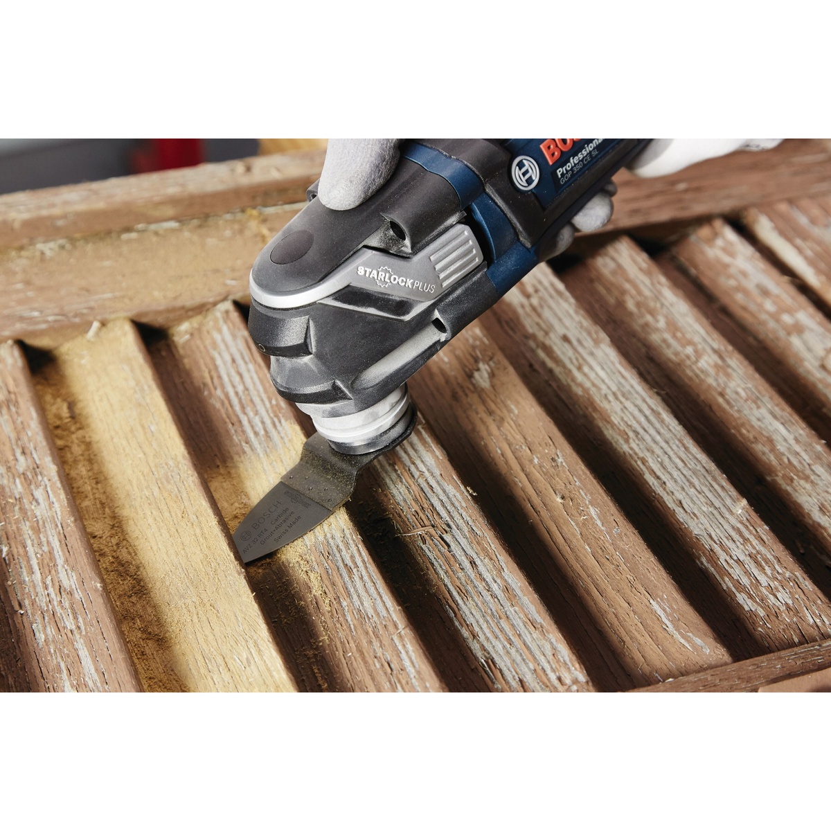 Bosch OSL200CR 2 In. Starlock Carbide Grit Sanding Finger sanding narrow wood grooves on a weathered wooden surface during detail refinishing work