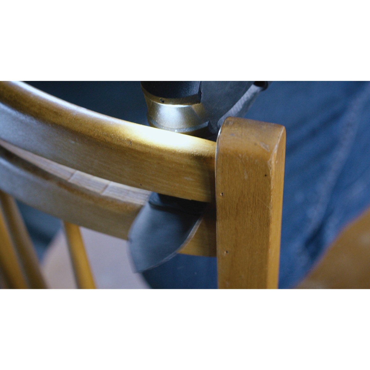Bosch OSL200CR 2 In. Starlock Carbide Grit Sanding Finger working around a curved wooden chair frame during furniture refinishing