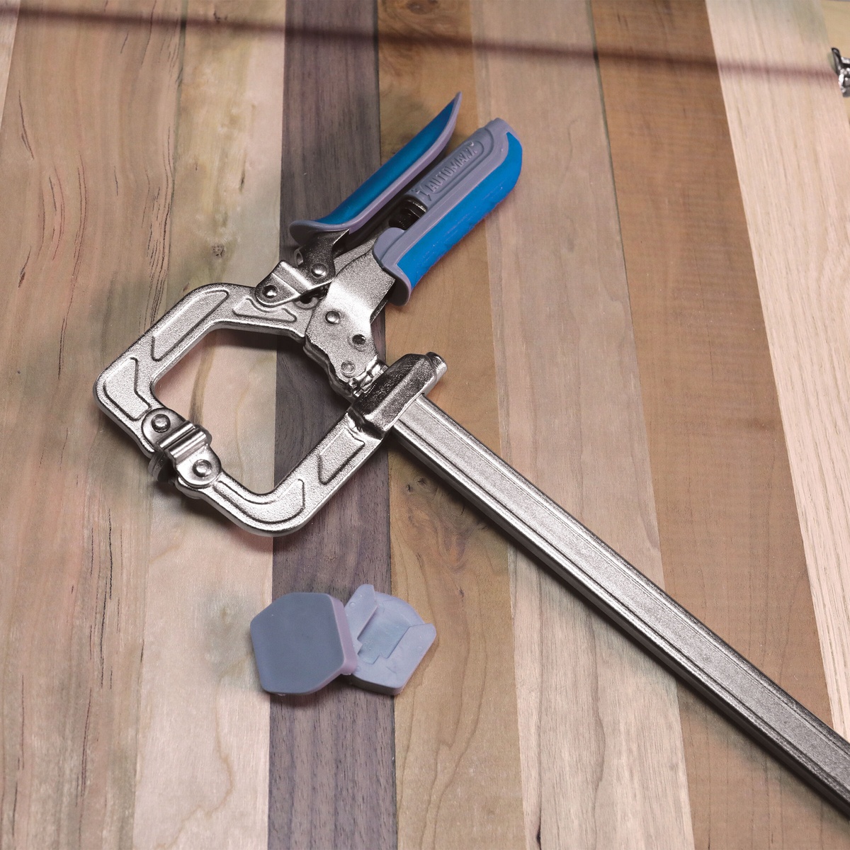 Kreg KSC16 Auto-Adjust Bar Clamp - 16 Inch resting on hardwood boards with clamp pads for woodworking glue-up work