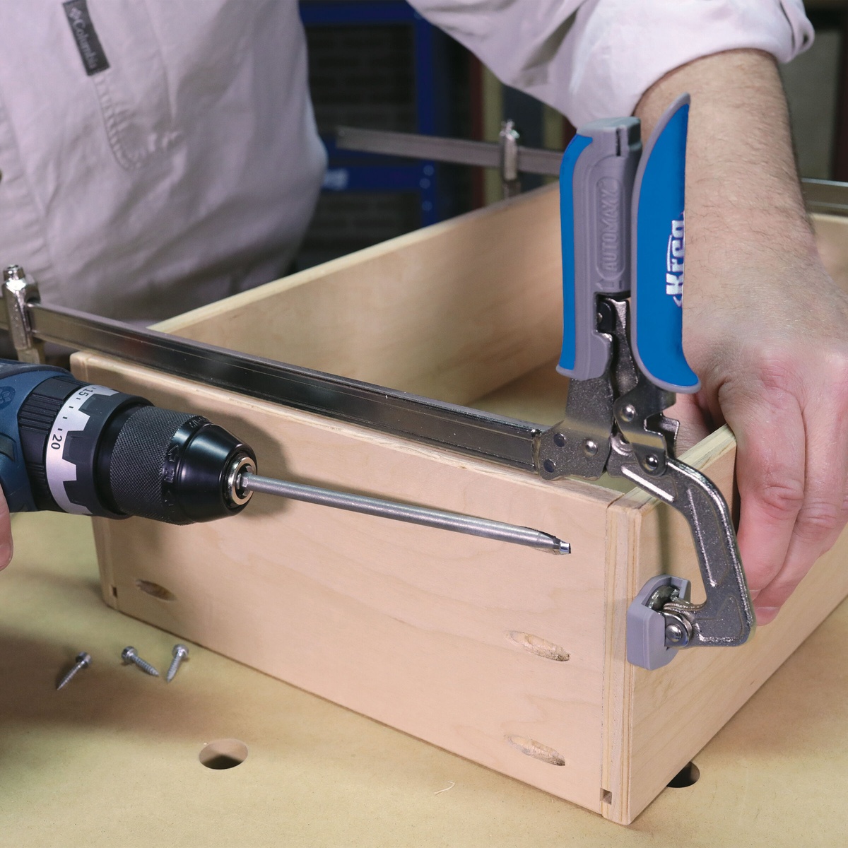 Kreg KSC16 Auto-Adjust Bar Clamp - 16 Inch securing a plywood box corner during cabinet assembly on a workbench
