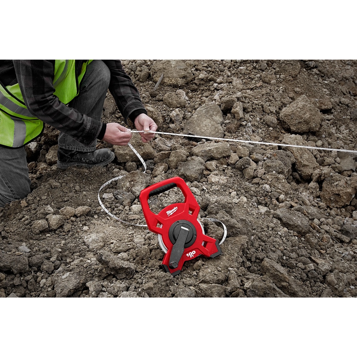 Milwaukee 48-22-5302 200Ft Fiberglass Open Reel Long Tape pulled across rough dirt for outdoor construction layout work