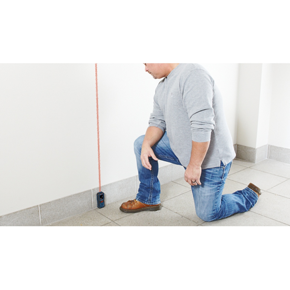 Bosch GLM165-22 BLAZE 165 Ft. Laser Measure checking vertical room height during interior layout work against a finished wall and tile floor