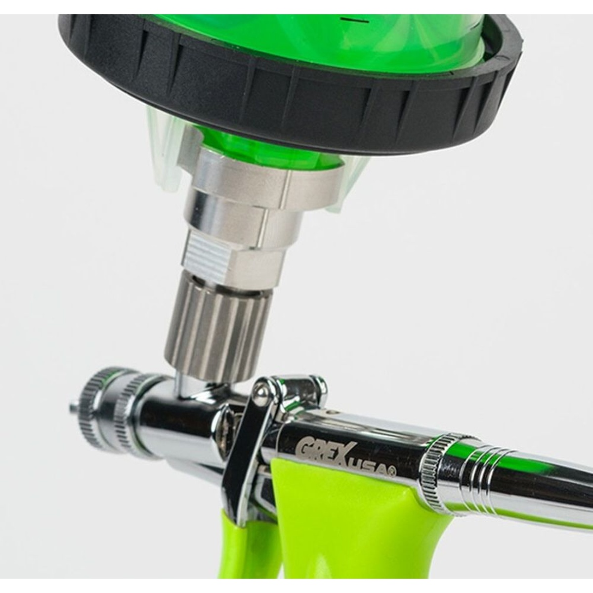 Grex AD33K Top Feed to Disposable Cups Adapter installed between a disposable paint cup system and a Grex top feed airbrush for spraying and finish work