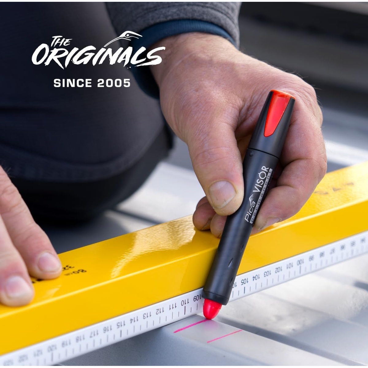 Pica 990/40 VISOR Luminescent Permanent Marker making a red layout mark along a straightedge on a metal work surface during measuring and fabrication