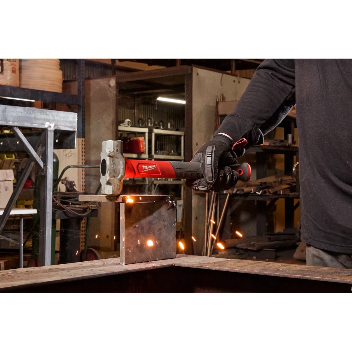 Milwaukee 48-22-9312 2.5lb Fiberglass Engineer Hammer striking metal on a fabrication table in a workshop jobsite setting