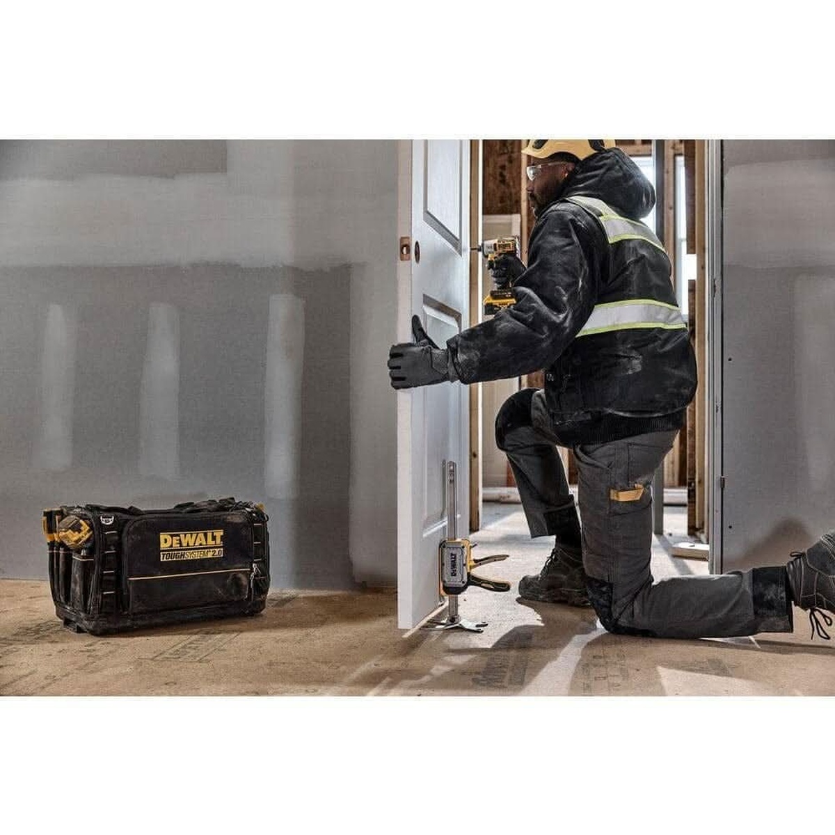 DEWALT DWHT83550 ToughSeries Construction Jack 8-3/4-in. Lift Height, 340 lb. Capacity, 2-Pack holding a door in position while a contractor fastens hardware indoors