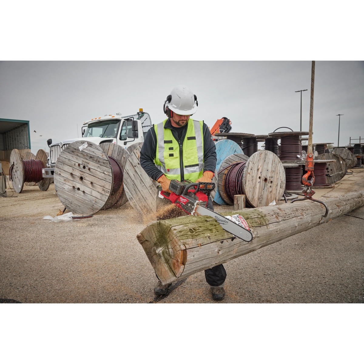 Milwaukee 20 in. Chainsaw Bar Guide with .325 in. Pitch and .050 in. Gauge installed on a cordless chainsaw cutting a utility pole on a jobsite