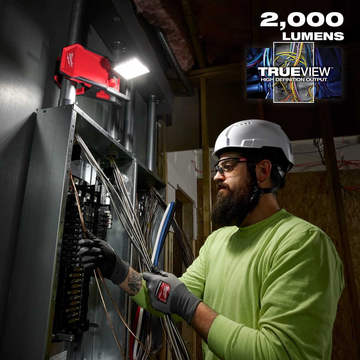 Milwaukee M18 ROVER Clamping Flood Light mounted overhead while illuminating electrical panel work in a jobsite interior