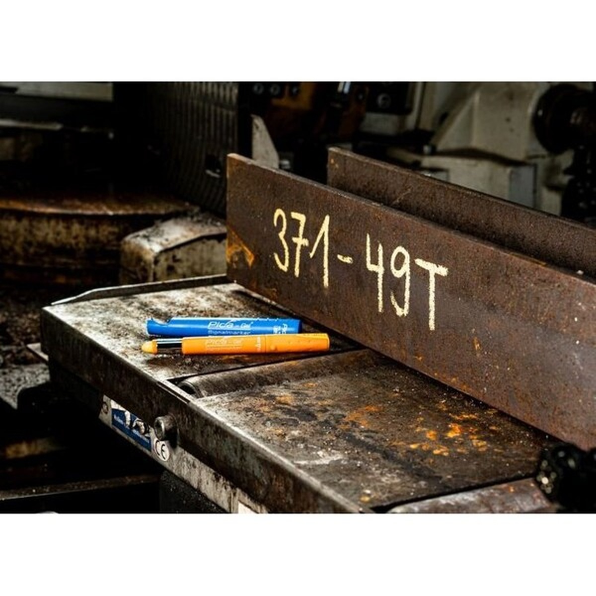 Pica 8084 Gel Signalmarker making bold yellow marks on dark structural steel in a fabrication shop environment