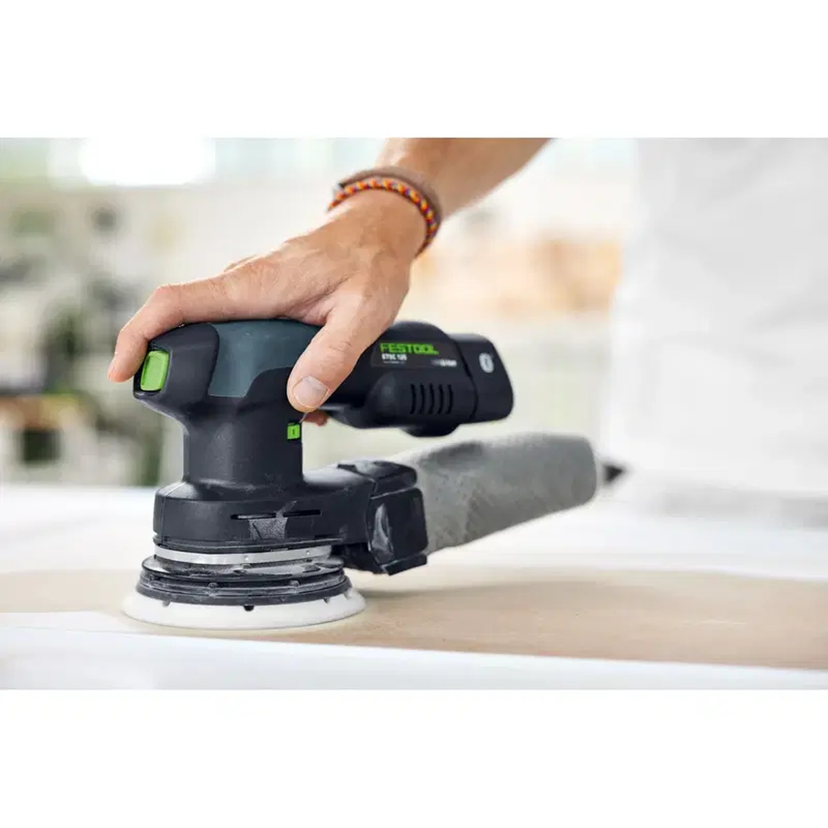 Festool 203306 Granat Net P150 Grit 6-Inch abrasive in use on a Festool random orbit sander smoothing a flat panel in a workshop setting