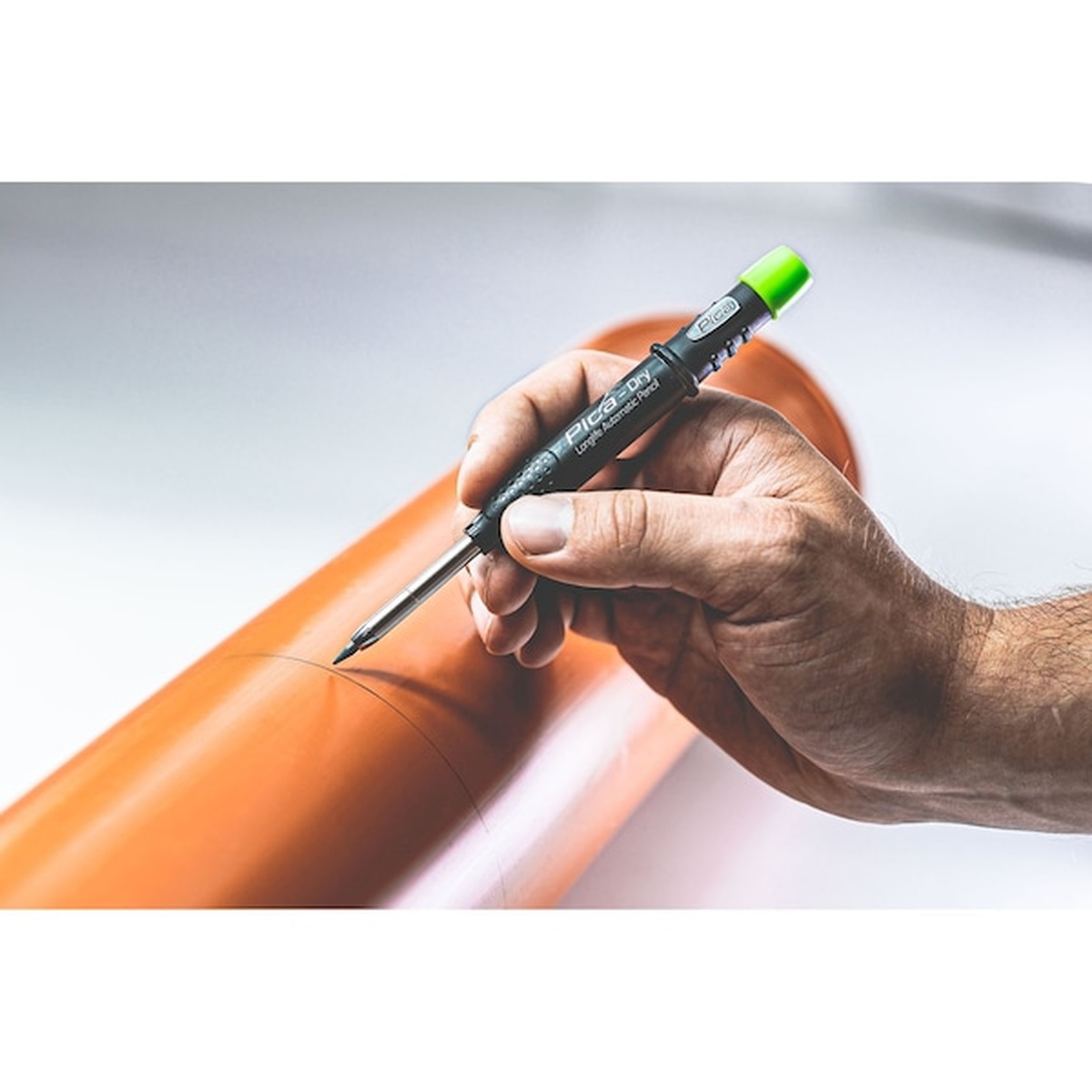 Pica Dry 3030/SB Longlife Automatic Pencil marking an orange PVC pipe during layout work on a jobsite
