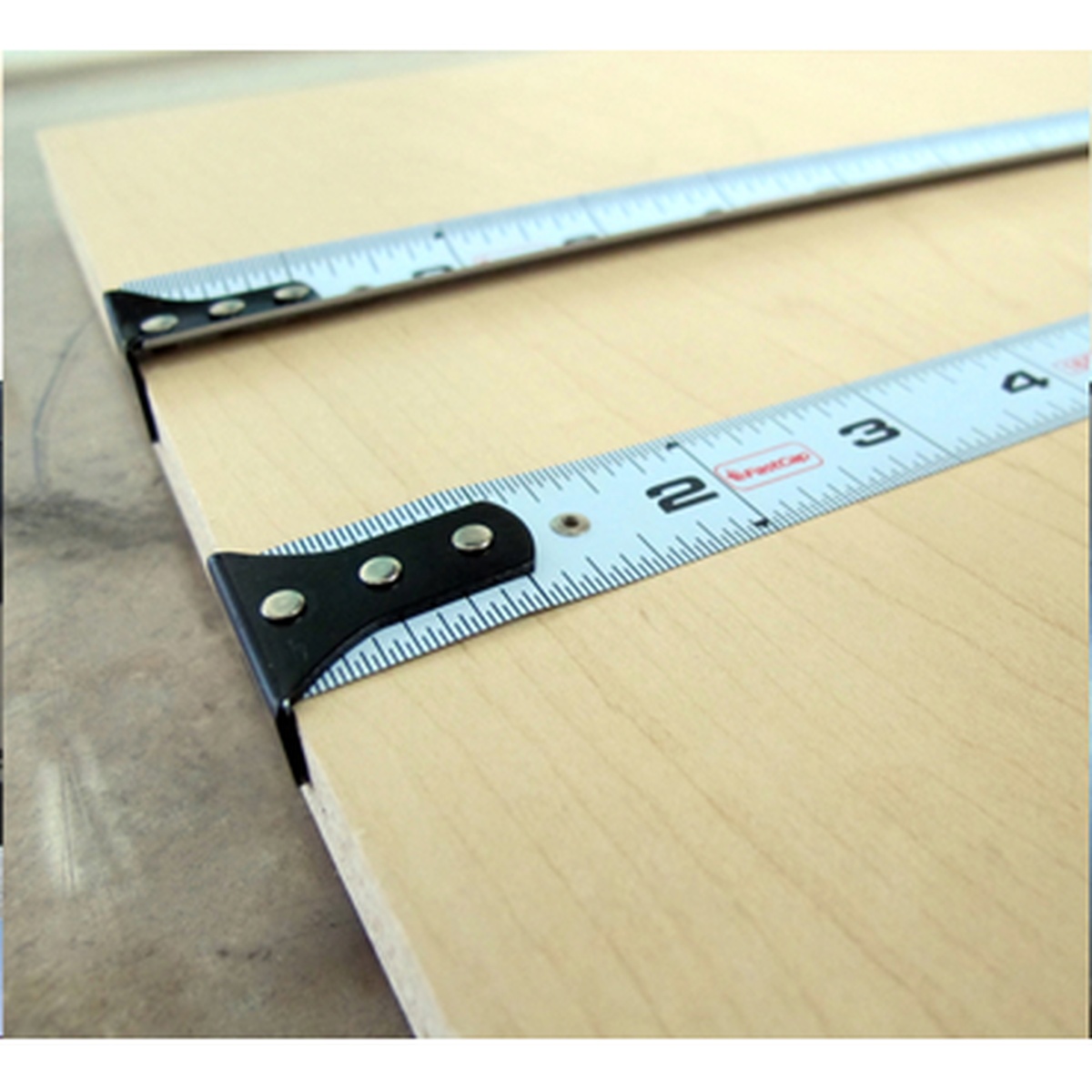 FastCap PMMR-FLAT 16 ProCarpenter FlatBack Tape Measure blade laid flat across a wood panel for precise edge marking in woodworking