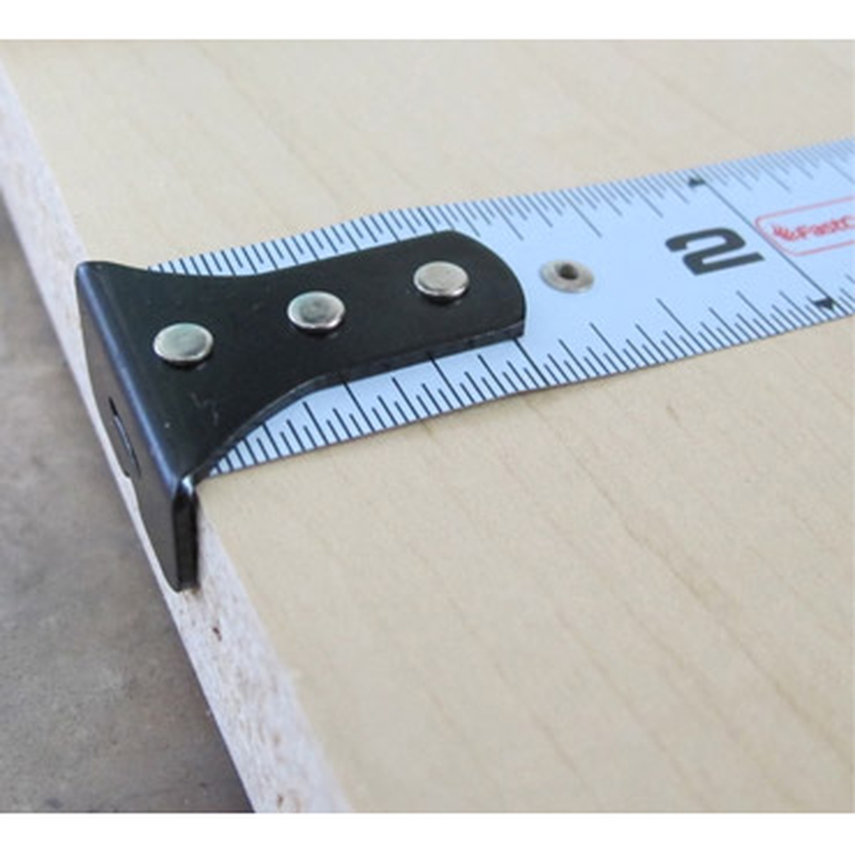 FastCap PMMR-FLAT 16 ProCarpenter FlatBack Tape Measure hooked on the edge of a wood panel during measuring and marking