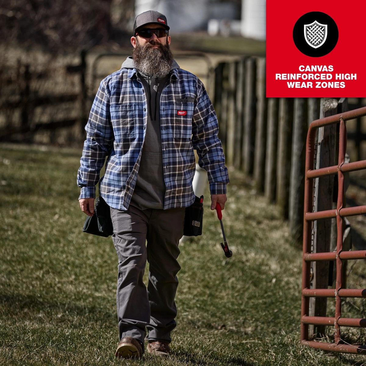 Milwaukee GRIDIRON Flannel Work Shirt worn outdoors during tool-carrying jobsite walking, showing reinforced workwear use in a field setting