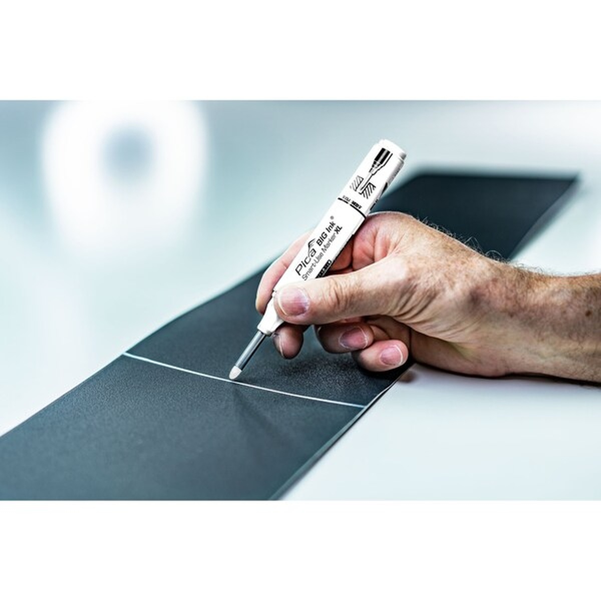 Pica Big Ink Smart-Use Marker XL white making a visible layout mark on a dark panel surface