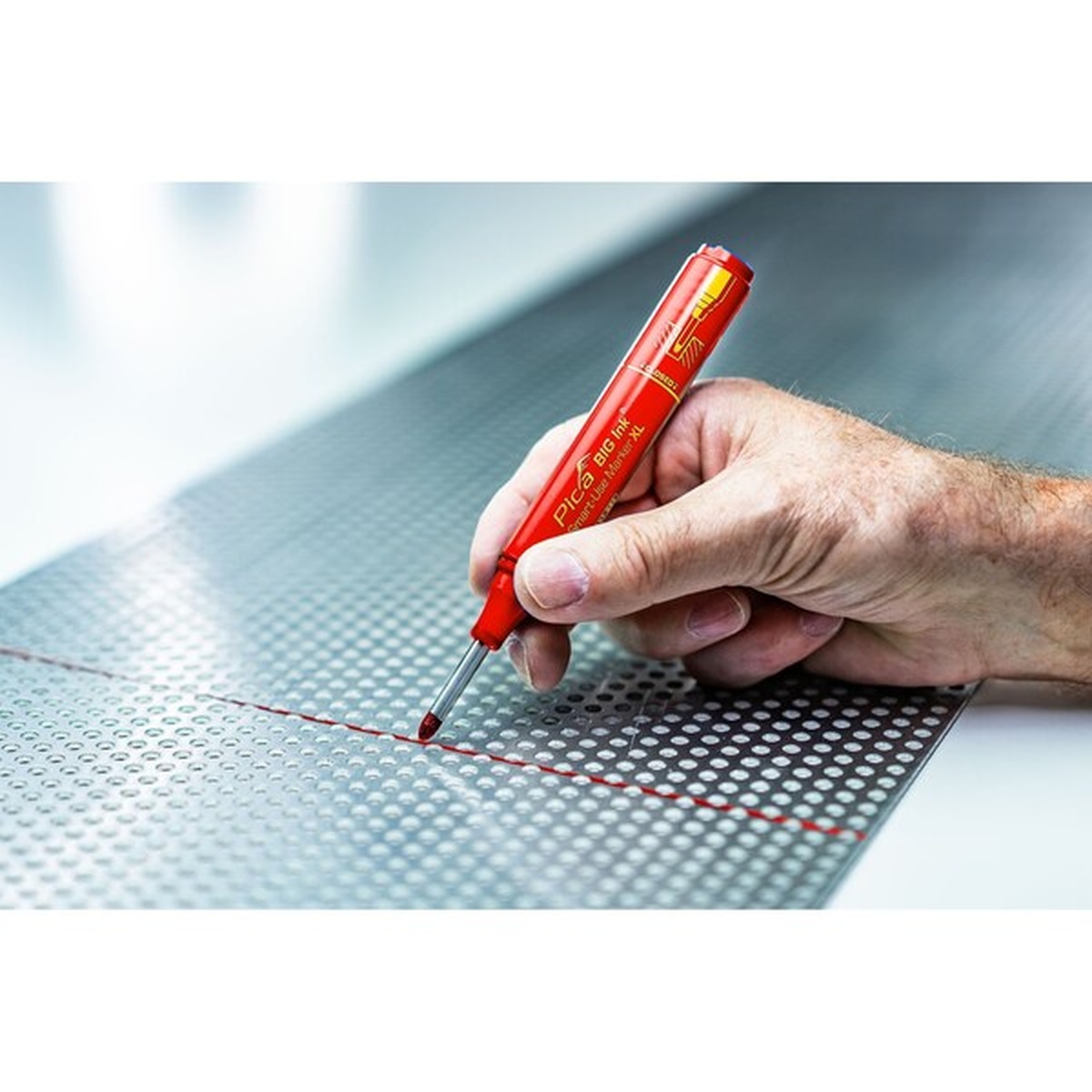 Pica 170/40/SB Red Ink Marker For Deep Hole drawing a red layout line on perforated sheet metal in a workshop setting