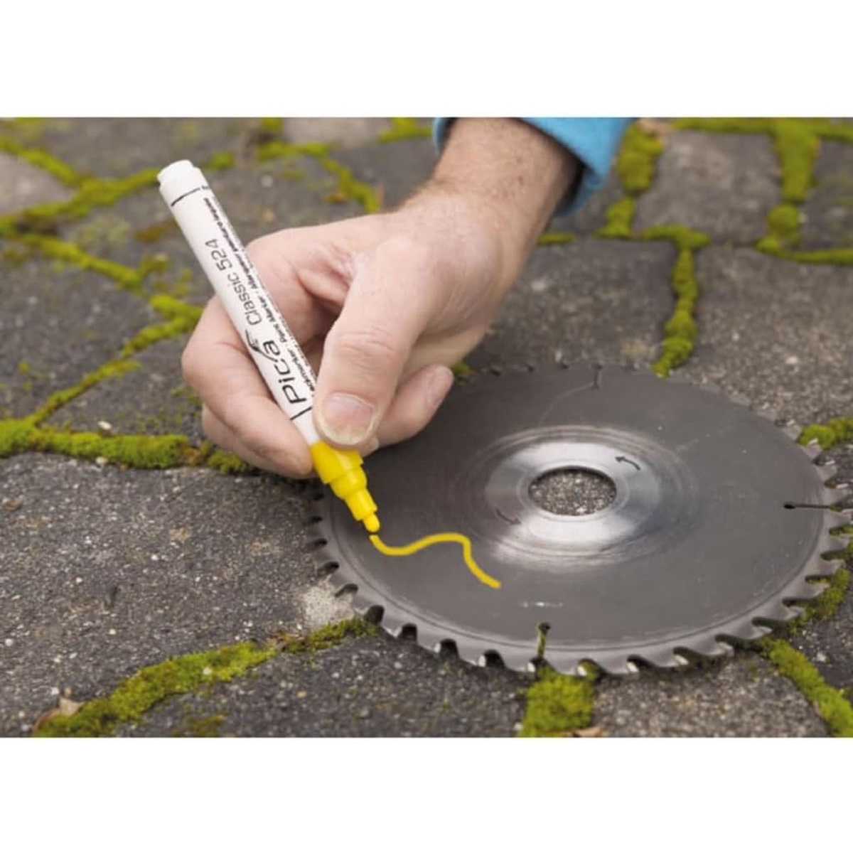 Pica 524/44 Yellow Paint Marker making a bright yellow mark on a metal circular saw blade during jobsite layout work