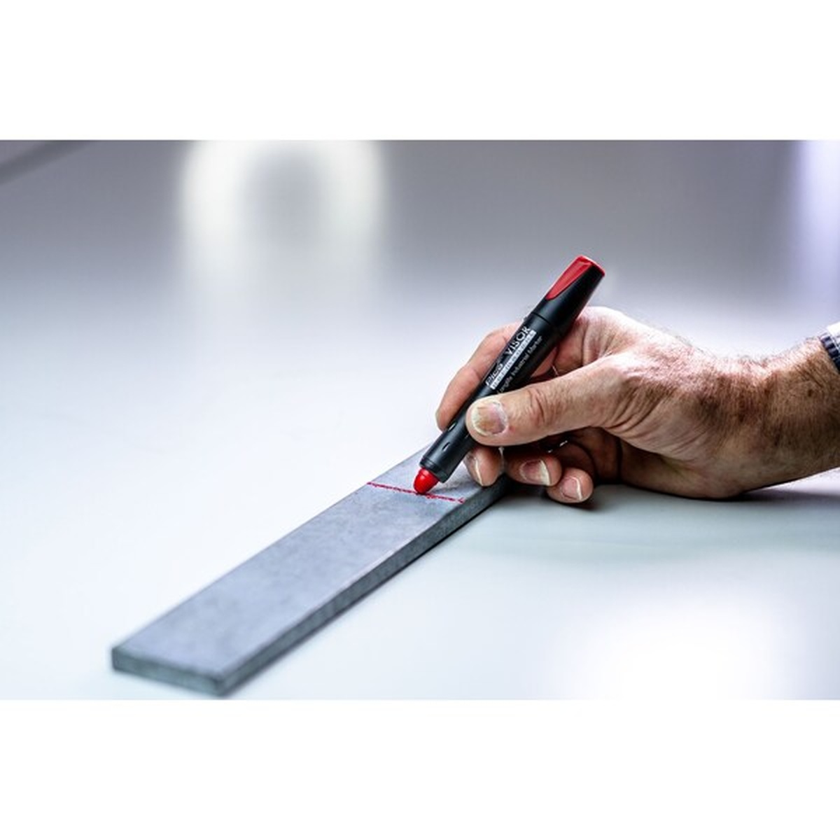 Pica 990/41/SB Visor Permanent Marker making a visible red layout mark on metal stock in a fabrication or shop setting