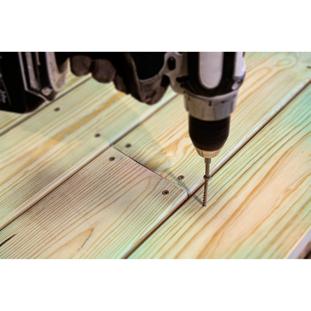 Simpson Strong-Tie DSVT3R770 Deck-Drive DSV Wood Screw being driven into treated deck boards with a drill during exterior deck fastening