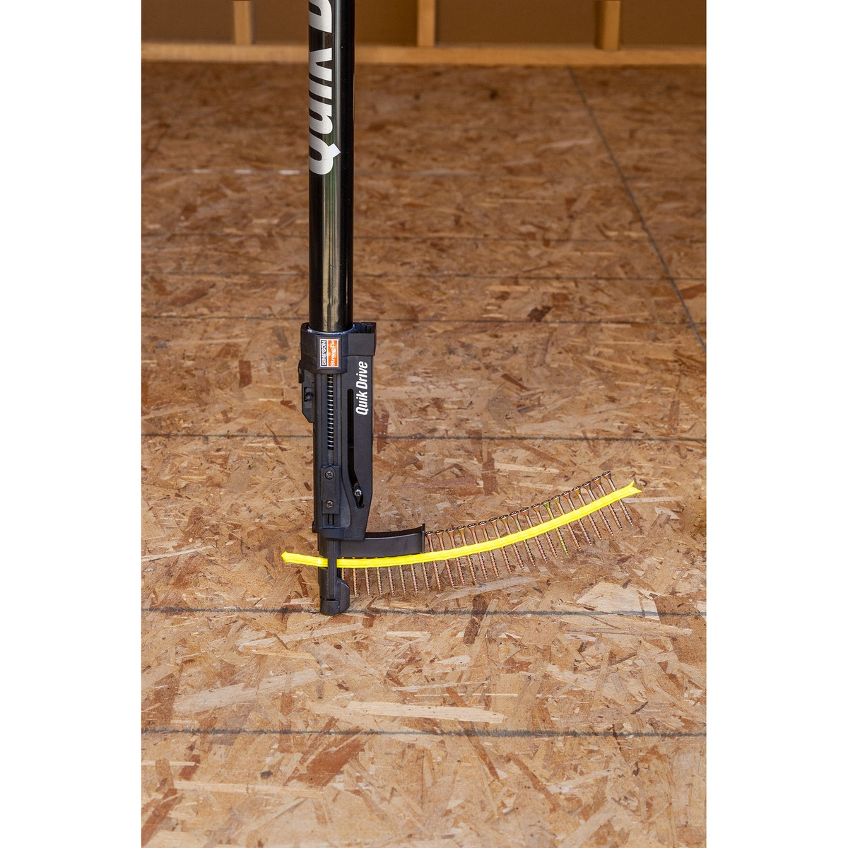 Simpson Strong-Tie Strong-Drive Subfloor Collated Screw strip loaded in a Quik Drive fastening tool on a wood subfloor panel