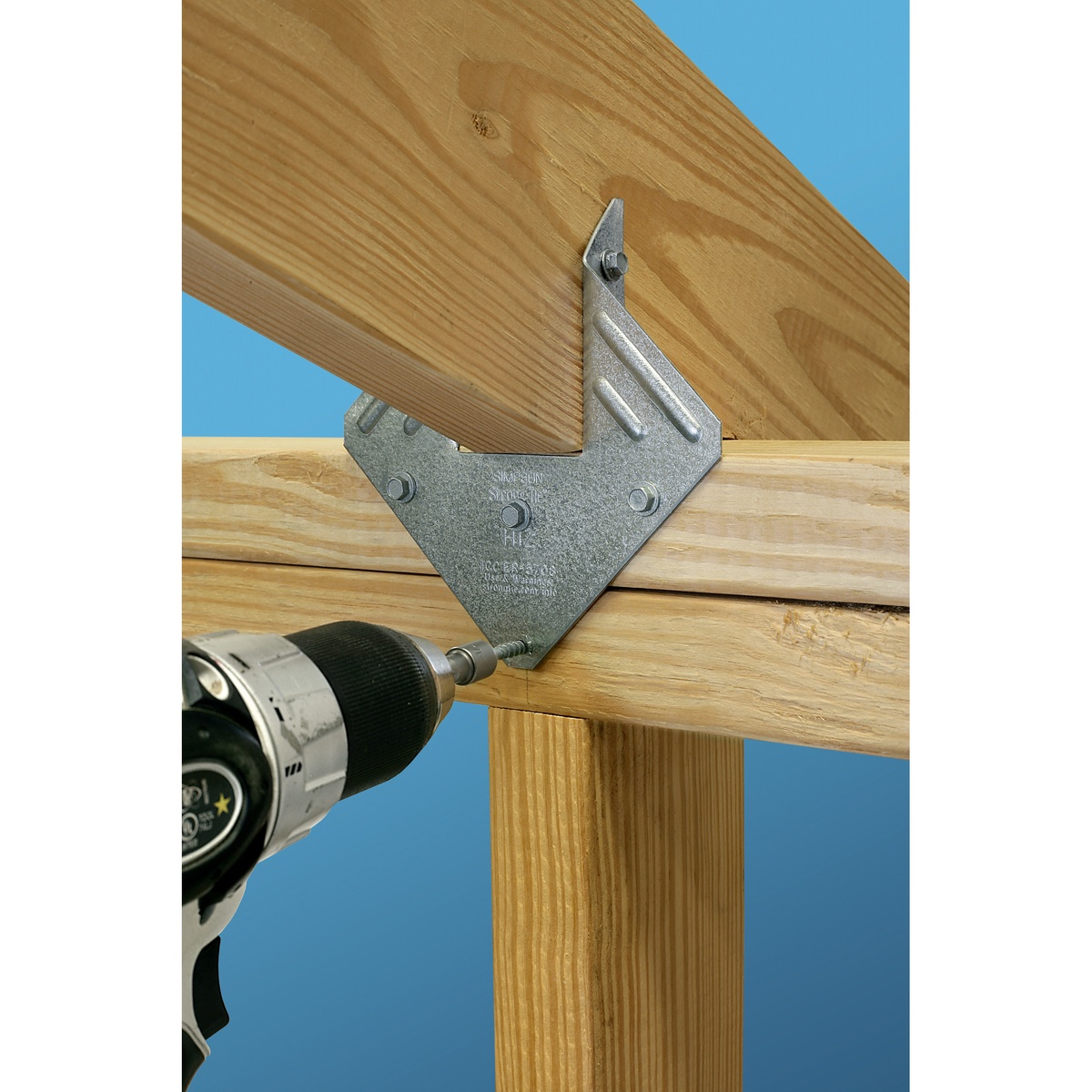 Simpson Strong-Tie SD10212R500 Strong-Drive SD Connector Screw being driven into a hurricane tie on wood framing with a drill during structural connector installation