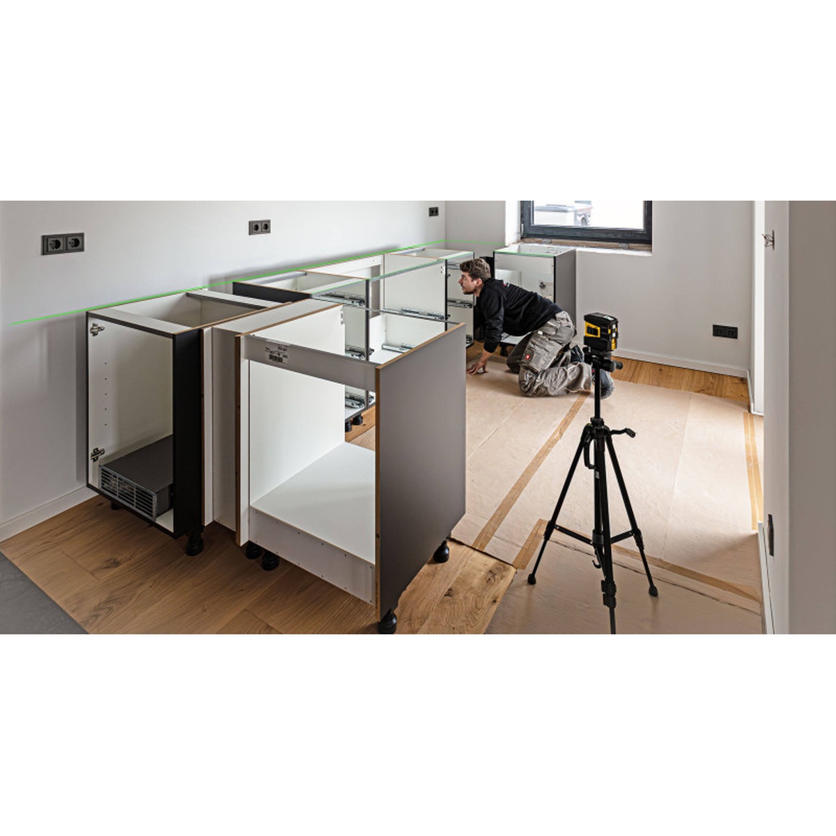 Stabila 03280 LAX 60 G Green Cross Line Laser Level projecting a green level line for kitchen cabinet installation in an interior remodeling workspace
