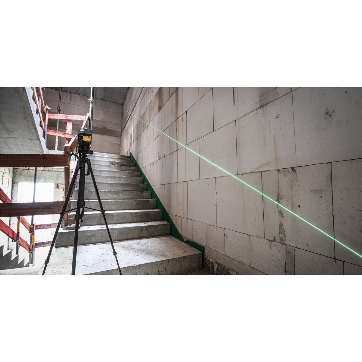 Stabila 03280 LAX 60 G Green Cross Line Laser Level used on a tripod to project an angled green line along a stairwell wall during construction layout