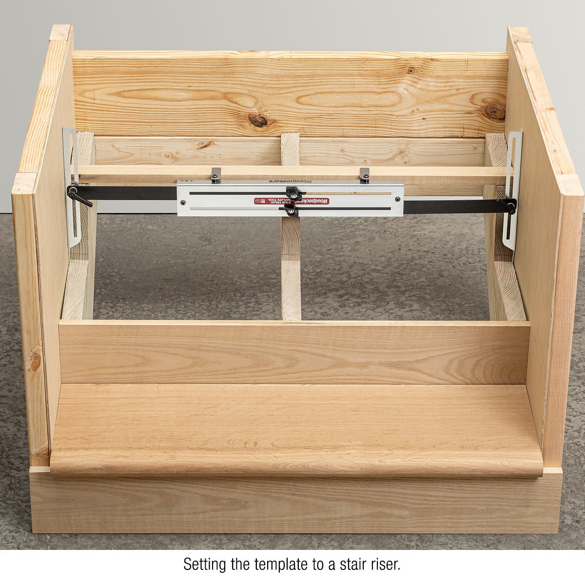 Woodpeckers Stair Tread Template Tool adjusted across a stair riser opening for stair tread layout in a remodeling or finish carpentry setting