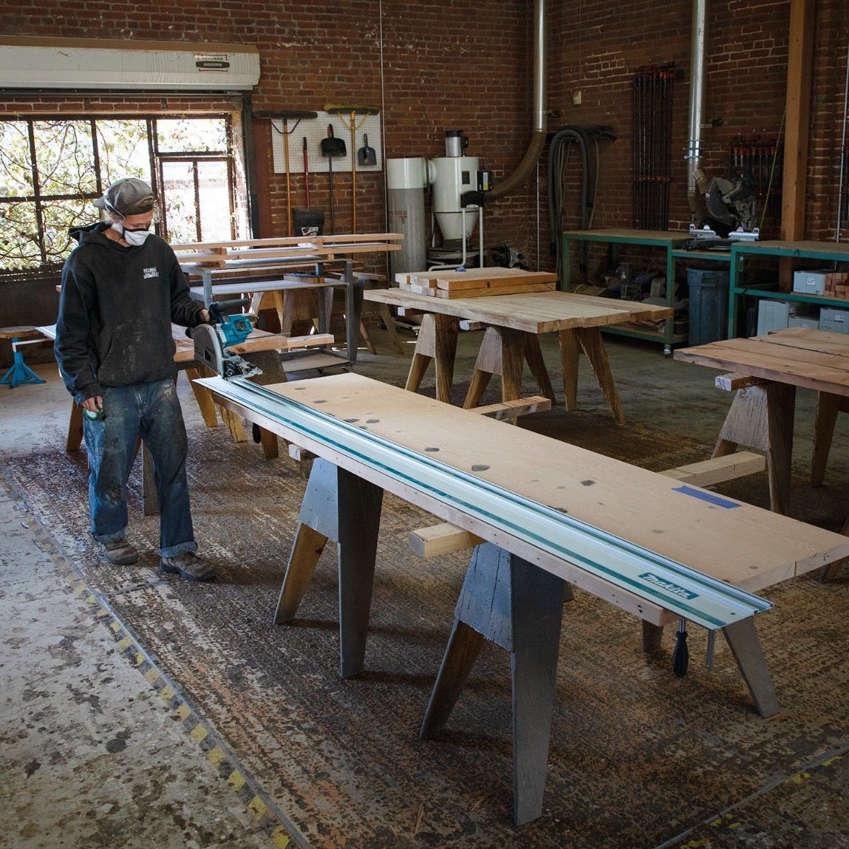 Makita 194367-7 118 inch guide rail used with a track saw to rip sheet material on a workbench