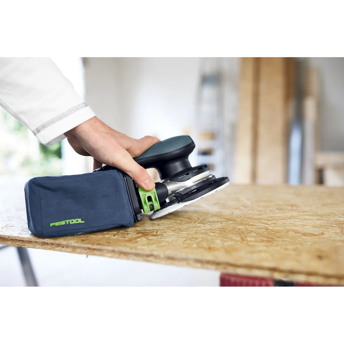 Festool SB-Longlife ETSC 2 Dust Collection Bag attached to a cordless sander while sanding an OSB work surface in an indoor jobsite setting