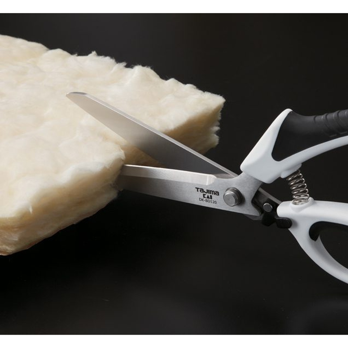 Tajima VARIX Single Ring Shears cutting thick insulation material in a close-up jobsite-style application shot