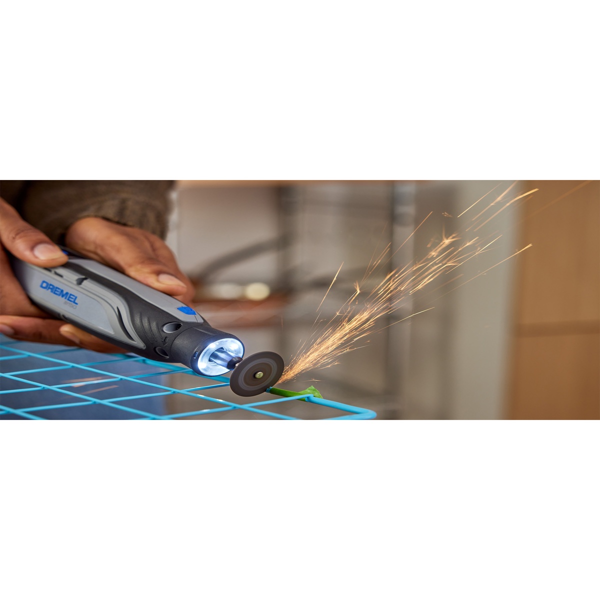 Dremel 8150-N/20 Brushless USB-C Rechargeable 8V Rotary Tool with LED Work Light cutting coated wire shelving indoors with sparks visible and the LED ring lighting the work area