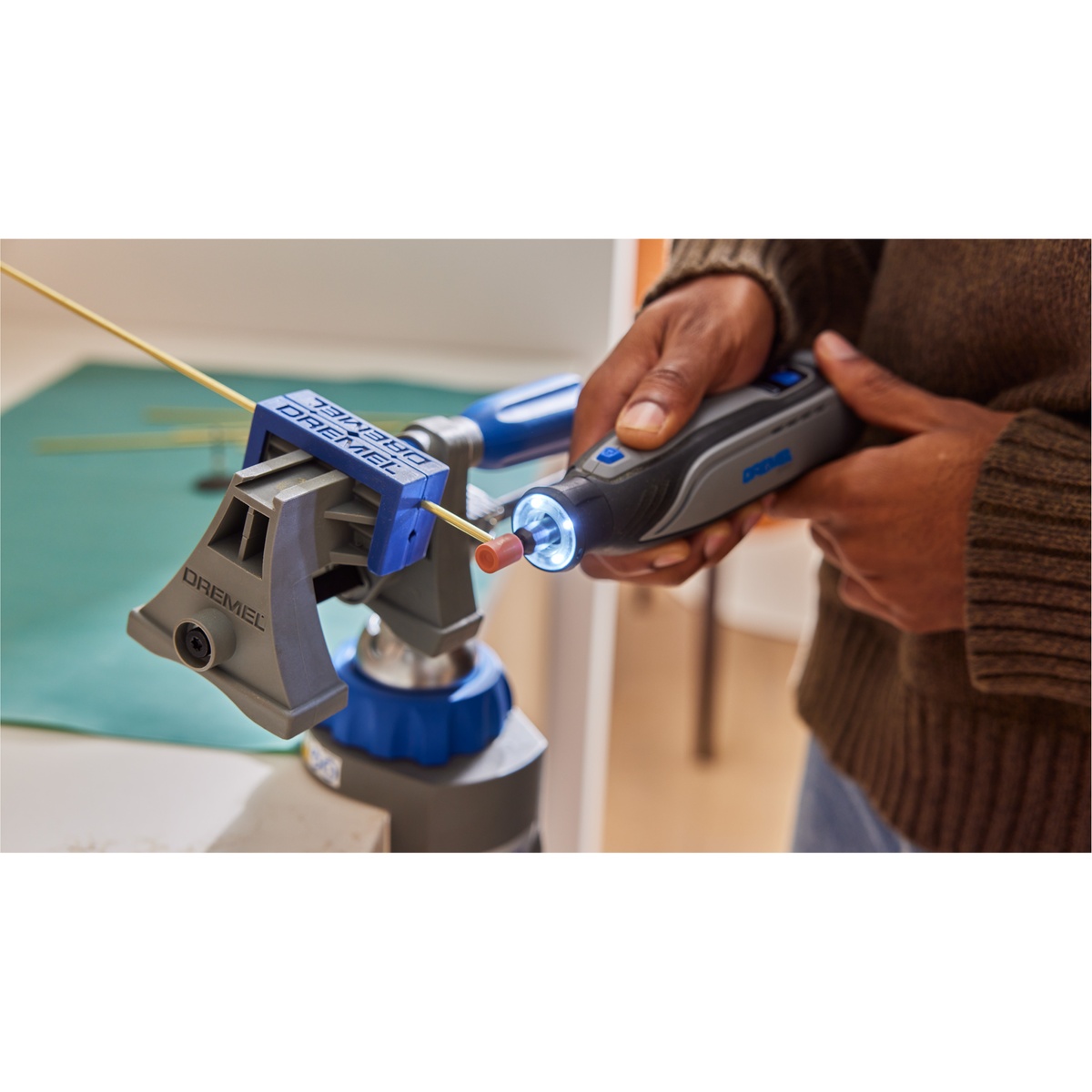 Dremel 8150-N/20 Brushless USB-C Rechargeable 8V Rotary Tool with LED Work Light shaping a small metal rod in a vise on a workbench for precision detail work