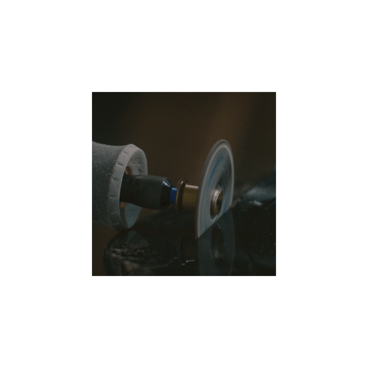 Dremel EZ Lock cutting wheel in use on a rotary tool making a cut on dark material during close-up shop work