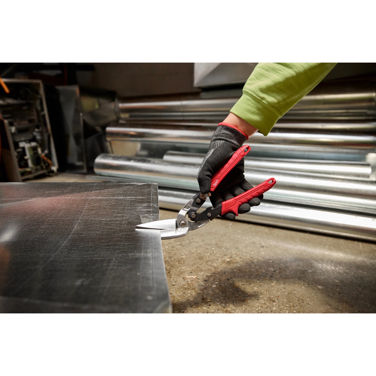 Milwaukee 48-22-4568 Left Offset Long Cut Aviation Snips cutting sheet metal on a shop floor during HVAC fabrication work