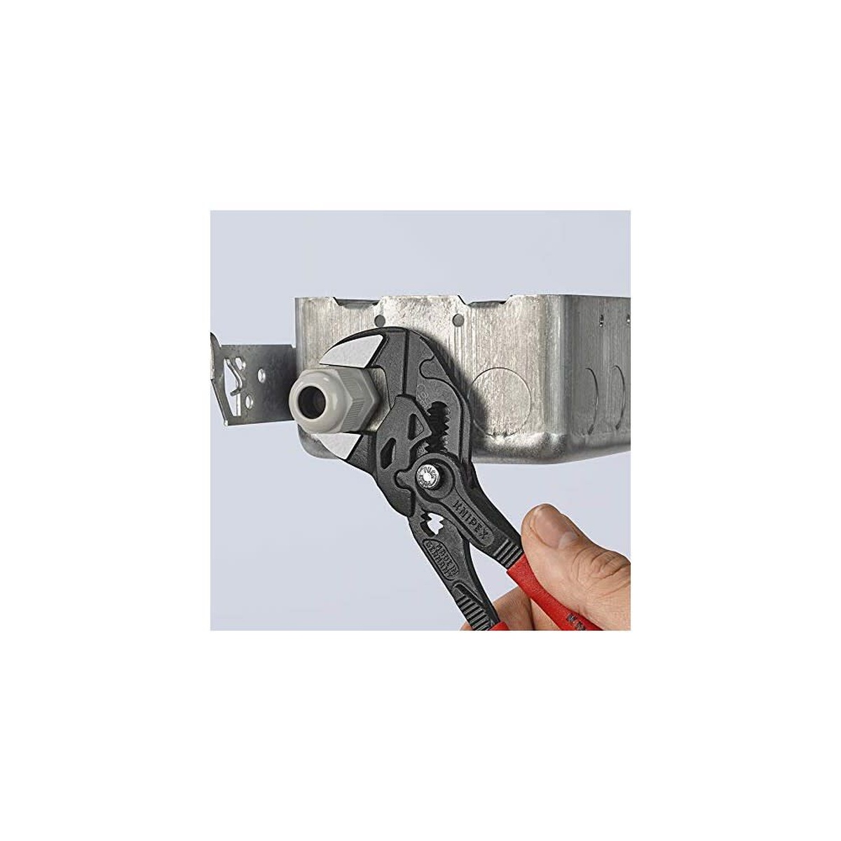 Knipex pliers wrench holding a conduit fitting and locknut inside a metal electrical box during installation work