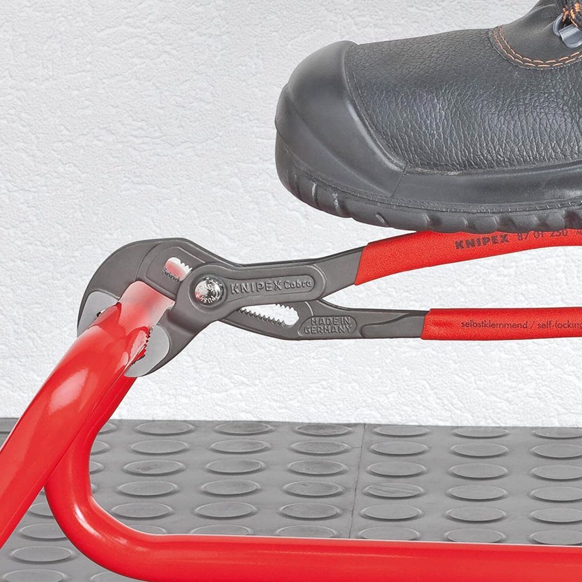 Knipex Cobra Hightech Water Pump Pliers 150mm gripping a red metal tube in a workshop setting where compact access and strong holding power matter