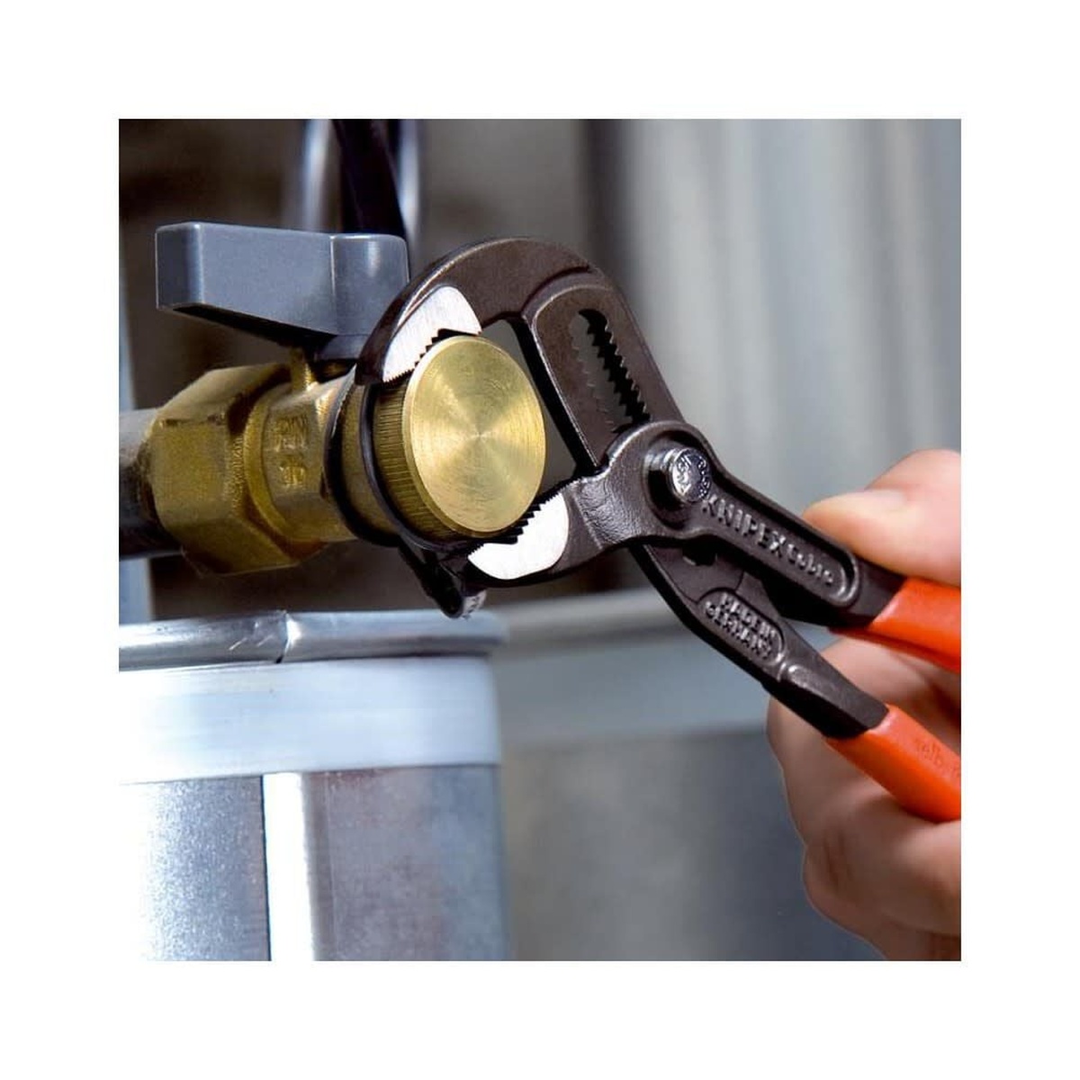 Knipex Cobra Hightech Water Pump Pliers 250mm gripping a brass plumbing fitting on installed piping during service work