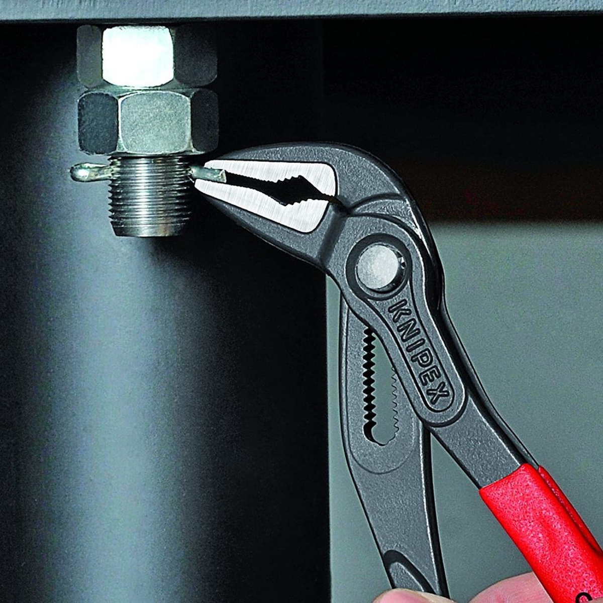 Knipex Cobra Extra Slim Water Pump Pliers 250mm gripping a small metal fastener on a threaded fitting in a tight equipment space