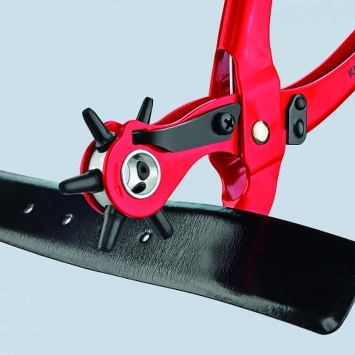 Knipex 90 70 220 Revolving Punch Pliers punching clean holes in a black leather strap during strap and belt adjustment work