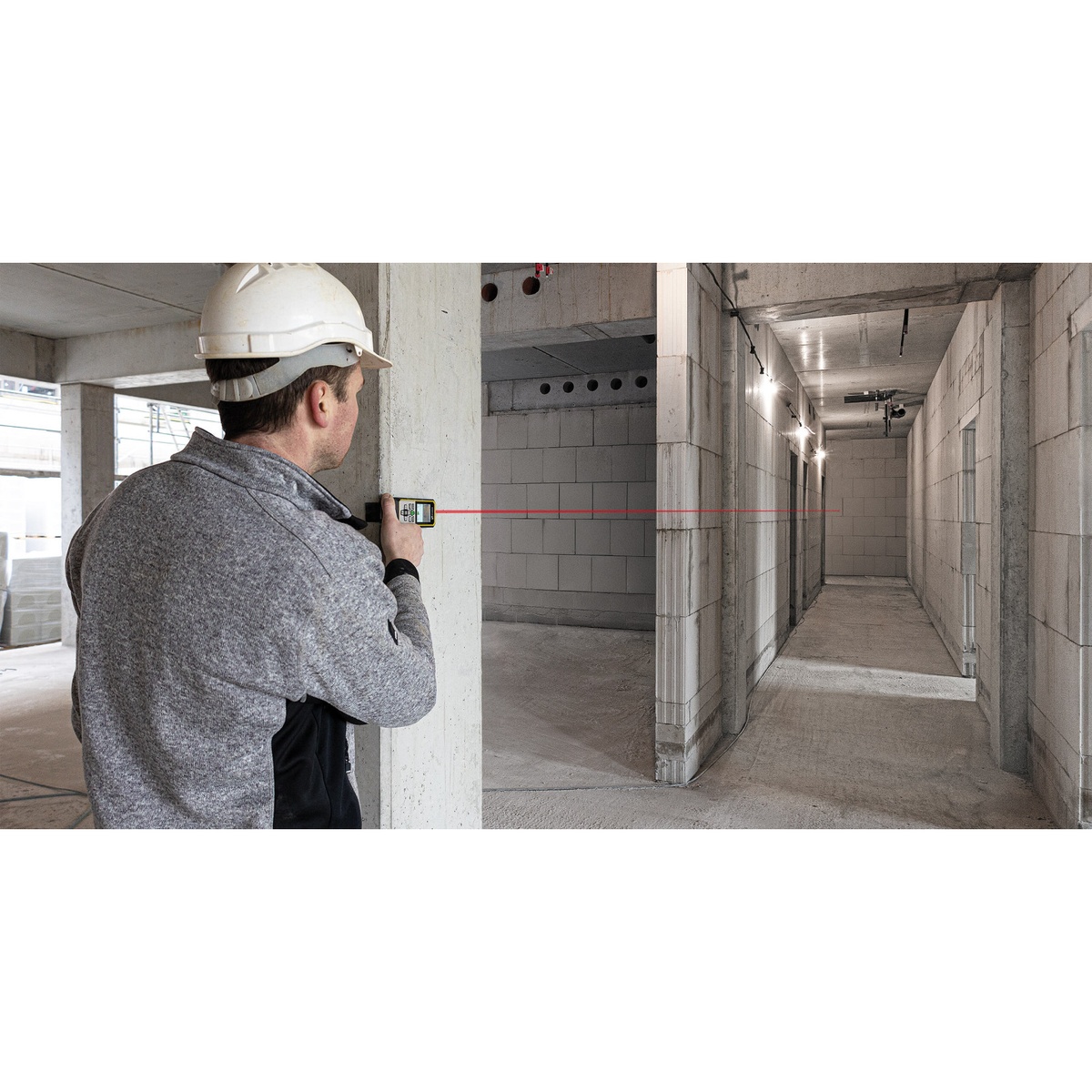 Stabila LD 530 BT 3.7V Battery Laser Distance Measurer with Bluetooth measuring a long concrete hallway on an active construction jobsite