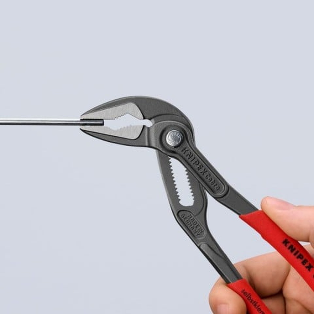 Knipex 87 51 180 Cobra ES Water Pump Pliers gripping a narrow metal rod during precision service work in a tight access area